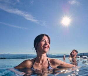 Frau entspannt im Infinity-Pools mit Blick auf das Panorama des Bayerischen Waldes.